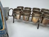 six cups on a metal rack with a bag in the background