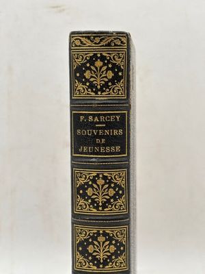 a black and gold book sitting on top of a white table