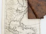 an old map and a leather book on a white surface