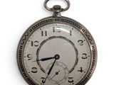 a silver pocket watch hanging on a white wall
