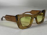 des lunettes de soleil marron aux verres verts posées sur une surface blanche