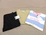 three t - shirts are sitting on a couch with a price tag