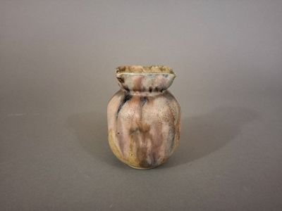 un petit vase posé sur une table, sur fond gris