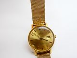 une image d'une montre-bracelet en or sur une surface blanche