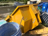 une benne basculante jaune posée par terre à côté d'un godet bleu