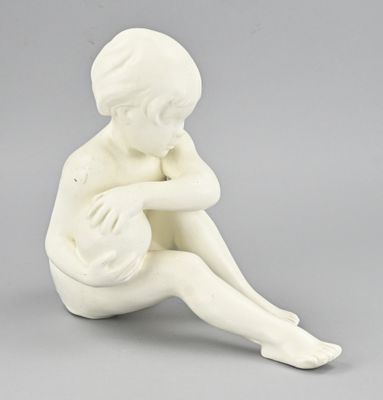 une figurine blanche représentant un garçon assis par terre