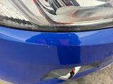 a close up of a blue car ' s headlight and front bumper