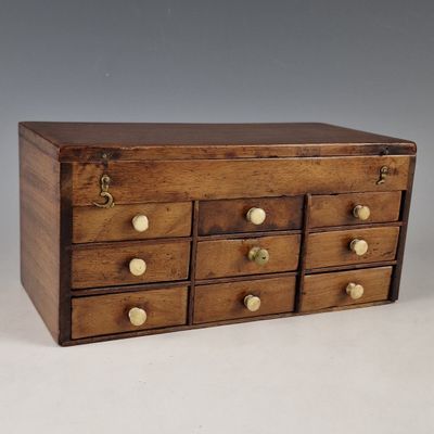 a small wooden box with many drawers on it