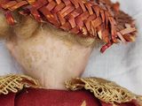 a doll that is wearing a brown hat and a red dress
