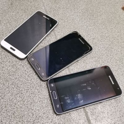 three cell phones are sitting on the floor next to each other