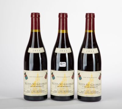 three bottles of red wine sit on a white surface