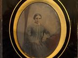 une vieille photo d'une femme en robe, assise sur une chaise