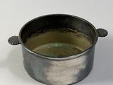 a small metal pot with a handle on a white surface