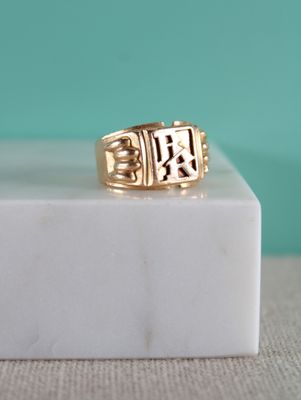 un gros plan d'une bague en or posée sur un bloc de marbre