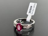 a close up of a diamond and ruby ring on a black surface