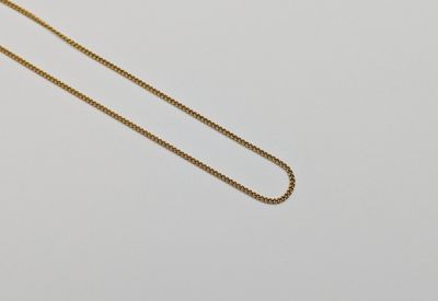 un gros plan d'un collier avec une chaîne en or sur une surface blanche