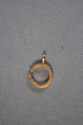un gros plan d'une bague plaquée or posée sur un tissu gris