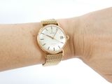 a woman ' s wrist that has a gold watch on it
