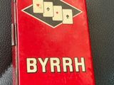 une boîte rouge ornée de cartes à jouer, posée sur un canapé