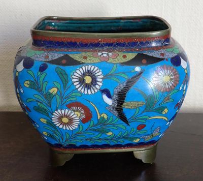 a blue vase with a bird on it sitting on a table