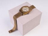 une montre en or posée sur un coffret rose