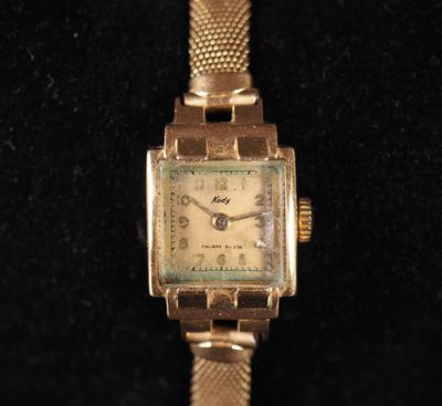 une image représentant une montre en or posée sur une surface noire