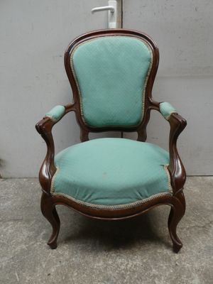 une vieille chaise dont l'assise est recouverte de tissu bleu