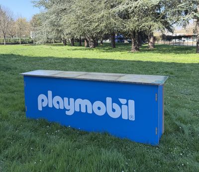 une boîte bleue avec un logo dessus, posée dans l'herbe