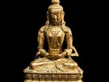 une statue en or représentant un Bouddha assis sur un socle noir