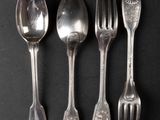 four silver spoons and two silver forks on a black surface