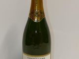 bottle of champagne on a white table with a white wall in the background