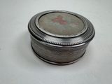 a small silver box with a picture on it