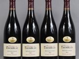 three bottles of red wine are lined up on a table