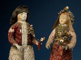 two figurines of people dressed in traditional clothing standing next to each other