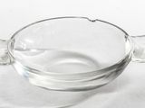 un saladier en verre muni d'une poignée, posé sur une surface blanche