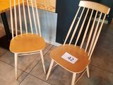 two wooden chairs sitting next to a table in a room