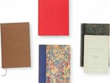 several books are lined up on a white surface with a red cover