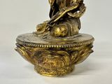 a gold statue of a man sitting on a bowl