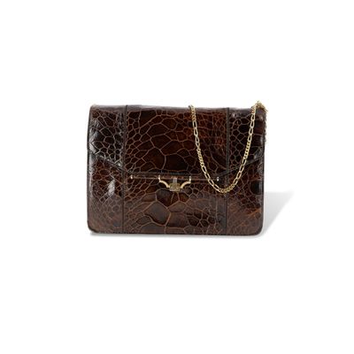 La pochette en cuir de crocodile marron est ornée d'une chaîne dorée sur le devant