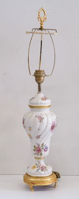 une lampe blanche avec un pied doré orné d'un motif floral