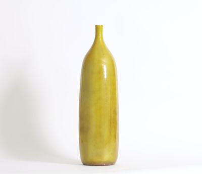 un vase jaune posé sur une surface blanche