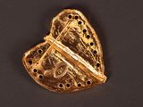 an image of a gold heart shaped brooch on a black surface