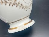a white vase with a gold design on it