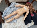 a doll that is laying on a chair with clothes on it