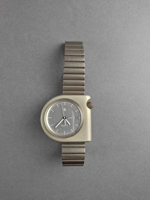 an image of a silver watch on a gray surface with a gray background