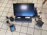 un ordinateur portable posé sur un sol carrelé, à côté d'autres appareils électroniques