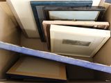 a cardboard box full of framed pictures and other items
