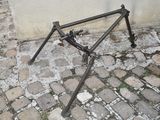 a broken bicycle frame sitting on the ground next to a wall