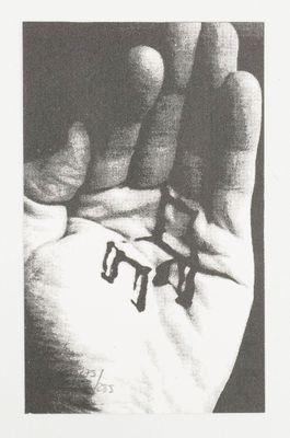black and white photograph of a person ' s hand holding two small letters