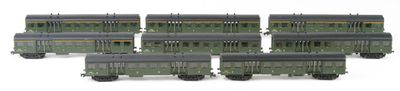 six green train cars sitting next to each other on a white surface